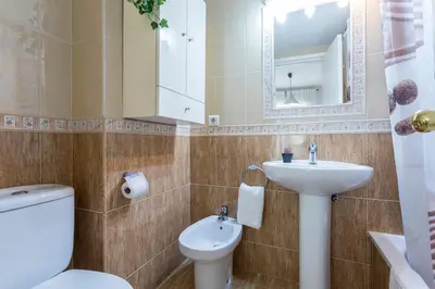 a bathroom with a sink and a toilet and a mirror at Brisas Estadio Playa Victoria in Cádiz