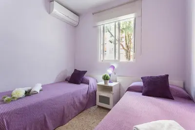two purple beds in a room with a window at Brisas Estadio Playa Victoria in Cádiz