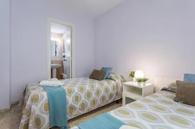 a bedroom with two beds and a mirror at Brisas Estadio Playa Victoria in Cádiz