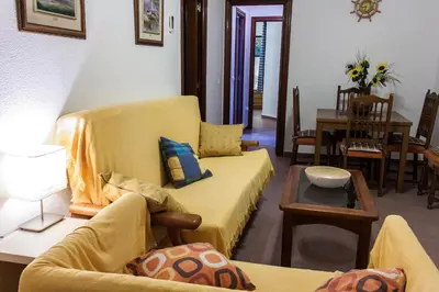 a living room with a yellow couch and a table at Apartamento La carraca in Chipiona