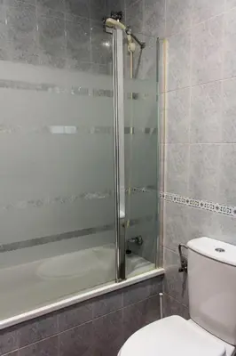 a bathroom with a toilet and a glass shower at Apartamento La carraca in Chipiona