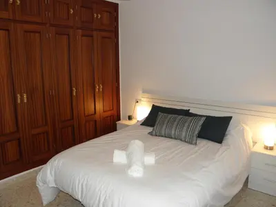 a bedroom with a large white bed with wooden cabinets at Apartamento en Jerez de la Frontera 2 in Jerez de la Frontera