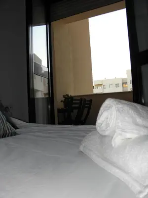 a bed with white sheets in a room with a window at Apartamento en Jerez de la Frontera 2 in Jerez de la Frontera