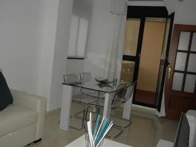 a glass table with chairs and a couch in a room at Apartamento en Jerez de la Frontera 2 in Jerez de la Frontera
