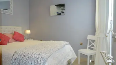 a white bedroom with a bed and a picture on the wall at Cosy Caleta Apartment in Cádiz