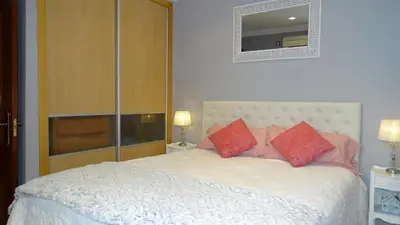 a bedroom with a white bed with red pillows at Cosy Caleta Apartment in Cádiz