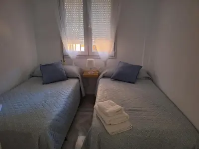 two twin beds in a room with a window at Apartamento Vespasiano in Chiclana de la Frontera