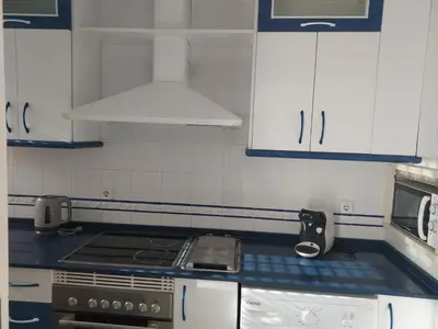 a kitchen with white cabinets and a stove top oven at Apartamento Vespasiano in Chiclana de la Frontera