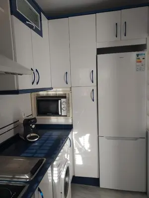 a small kitchen with white cabinets and a microwave at Apartamento Vespasiano in Chiclana de la Frontera