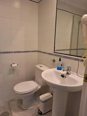 a white bathroom with a toilet and a sink at Apartamento Vespasiano in Chiclana de la Frontera