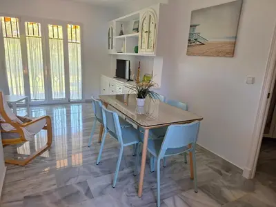 a dining room with a wooden table and blue chairs at Apartamento Vespasiano in Chiclana de la Frontera