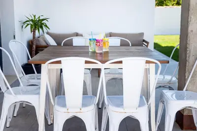 a wooden table and four white chairs on a patio at Villa La Barrosa in Chiclana de la Frontera