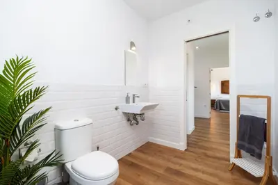 a white bathroom with a toilet and a sink at Villa La Barrosa in Chiclana de la Frontera