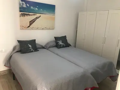a bedroom with a bed and a painting on the wall at Apartamento Marina el Puerto in El Puerto de Santa María