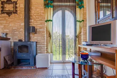 a living room with a fireplace and a table and a television at Atico Sanlucar in Sanlúcar de Barrameda