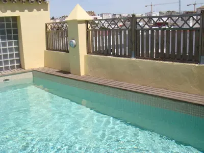 a swimming pool next to a building with a fence at La Casa del Limonero in El Puerto de Santa María