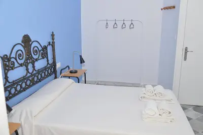 a bedroom with a bed with a white bedspread at Pensión Las Cuatro Naciones in Cádiz