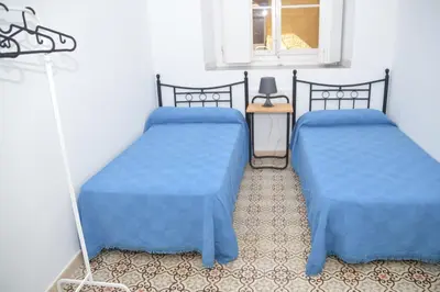 two beds with blue covers in a room at Pensión Las Cuatro Naciones in Cádiz