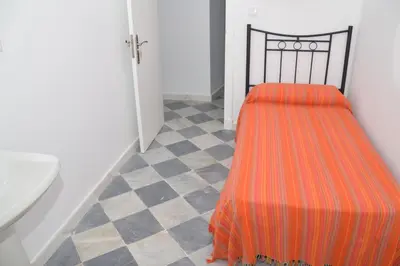 a bathroom with a bed with an orange blanket at Pensión Las Cuatro Naciones in Cádiz