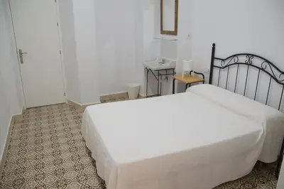 a bedroom with a large white bed in a room at Pensión Las Cuatro Naciones in Cádiz