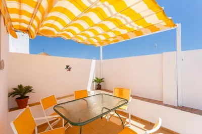 a table and chairs in a room with a yellow and white umbrella at El Mirador del CAMPANARIO by Cadiz4Rentals in Cádiz