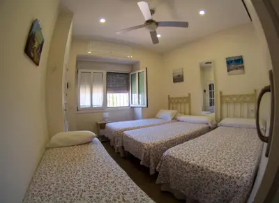 a room with three beds and a ceiling fan at Casita de María in El Puerto de Santa María