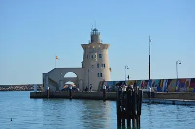 a lighthouse in the water with a chair in front of it at Casita de María in El Puerto de Santa María