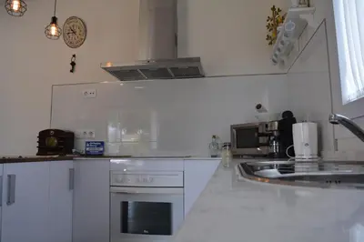 a white kitchen with a sink and a stove at Casita de María in El Puerto de Santa María