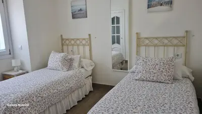 a bedroom with two beds and a mirror at Casita de María in El Puerto de Santa María