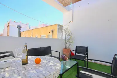 a table with a bottle of wine and an orange on a balcony at El Atico de las MARINAS free Parking by Cadiz4Rentals in Cádiz