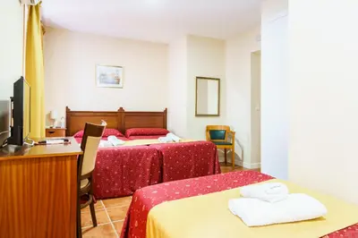 a hotel room with two beds and a desk at Hotel Carlos V Jerez by Vivere Stays in Jerez de la Frontera