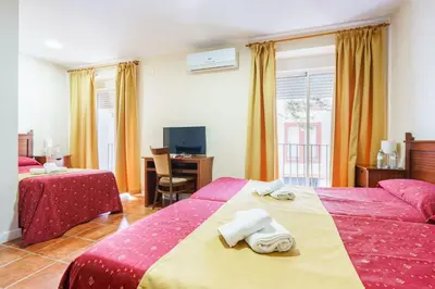 a hotel room with two beds and a desk at Hotel Carlos V Jerez by Vivere Stays in Jerez de la Frontera