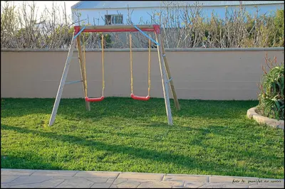 a playground with two swings in a yard at Mi Oasis in Conil de la Frontera