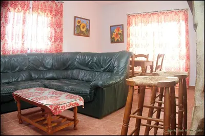 a living room with a black leather couch and wooden stools at Mi Oasis in Conil de la Frontera