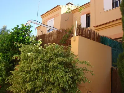 a tree in front of a house with a fence at Chalet Pto Sta Maria, SOLO FAMILIAS in El Puerto de Santa María