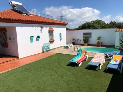 a backyard with a swimming pool and two lawn chairs at El Mirador de Bellavista in Conil de la Frontera