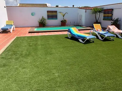 a lawn with lounge chairs and a swimming pool at El Mirador de Bellavista in Conil de la Frontera