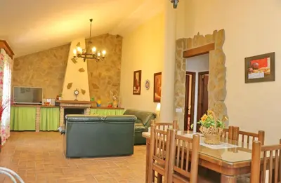 a living room with a dining table and a kitchen at Casa con piscina 92 in Conil de la Frontera