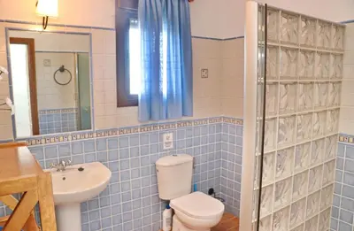 a blue tiled bathroom with a toilet and a sink at Casa con piscina 92 in Conil de la Frontera