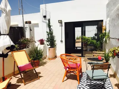 a patio with colorful chairs and a black door at Ático Falla in Cádiz