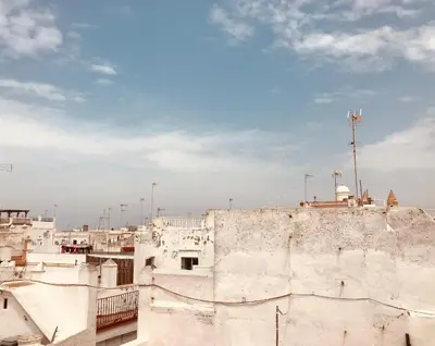 an old white building with a blue sky in the background at Ático Falla in Cádiz
