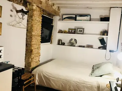 a bed in a room with white walls and shelves at Ático Falla in Cádiz