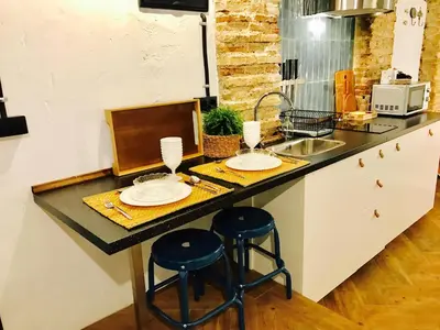 a kitchen counter with two stools and a sink at Ático Falla in Cádiz