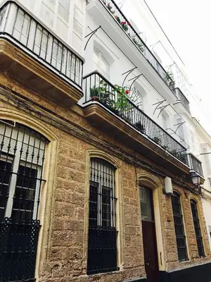 a brick building with a balcony with plants on it at Ático Falla in Cádiz