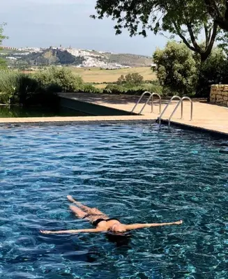 a woman laying on her back in a swimming pool at Cortijo Bablou in Arcos de la Frontera