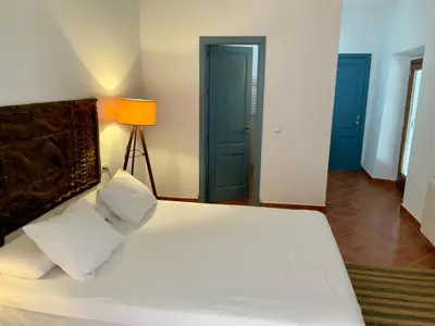 a bedroom with a large white bed and a lamp at Cortijo Bablou in Arcos de la Frontera