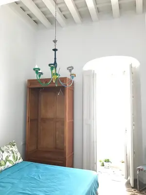 a bedroom with a blue bed and a chandelier at Apartamentos La Selva in Cádiz