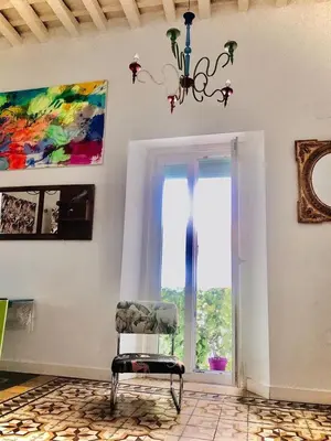 a room with a chair and a window and a chandelier at Apartamentos La Selva in Cádiz