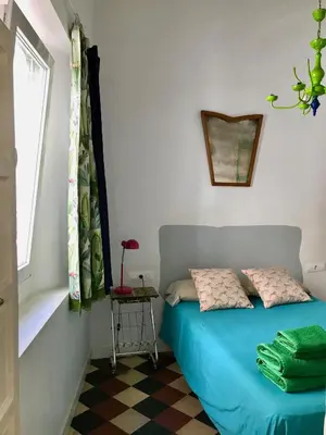 a bedroom with a blue bed and a window at Apartamentos La Selva in Cádiz