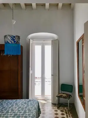 a bedroom with a bed and a window and a chair at Apartamentos La Selva in Cádiz